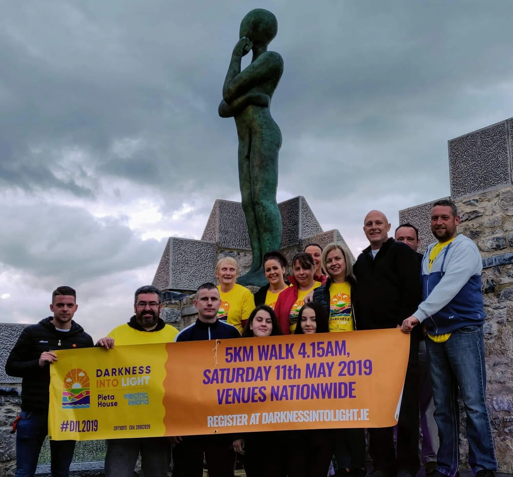 Group holding a Darkness Into Light banner beneath the bronze figure on the castle roof