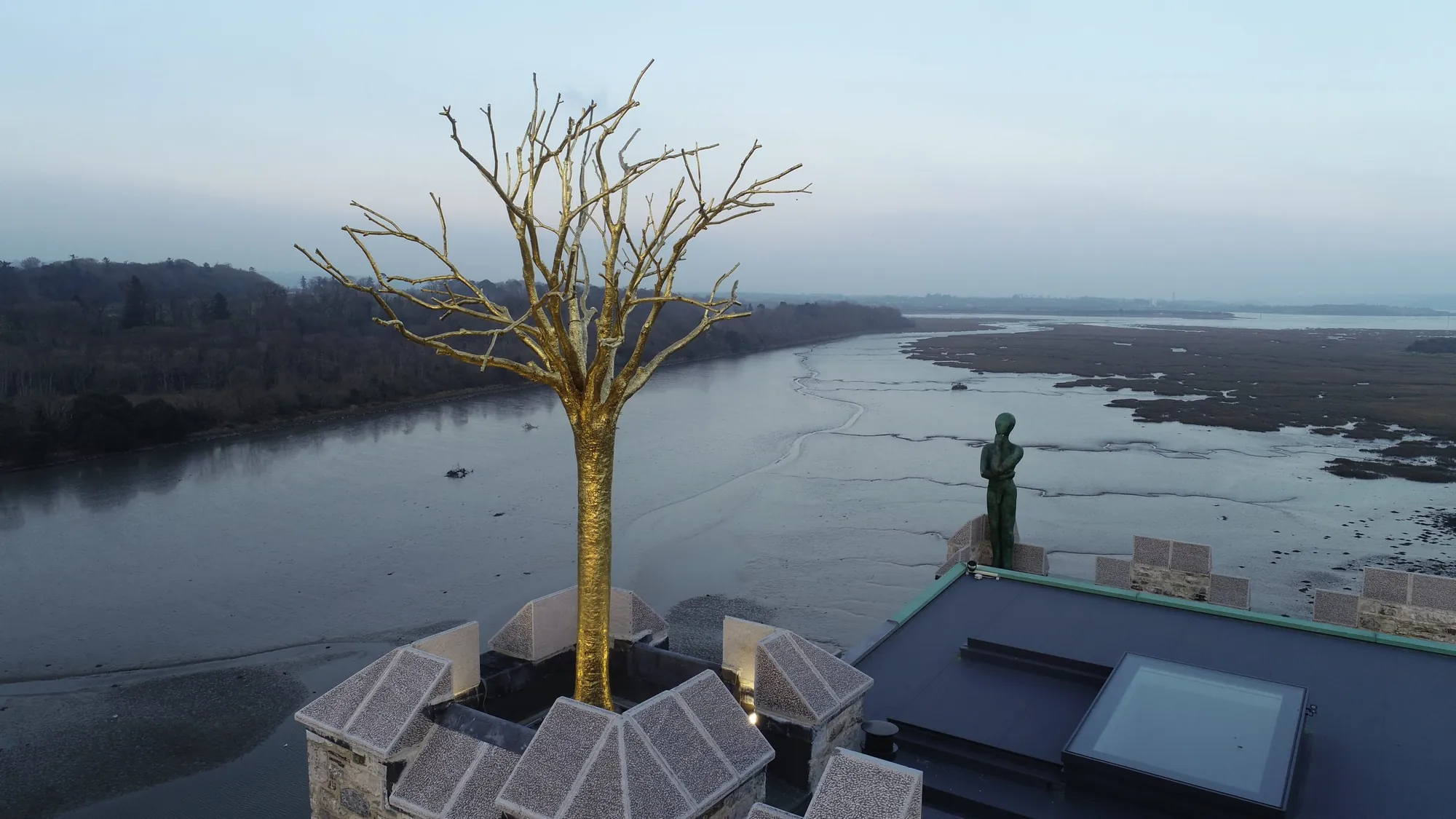 Aerial view of the castle rooftop showing the golden tree and bronze figure above the water