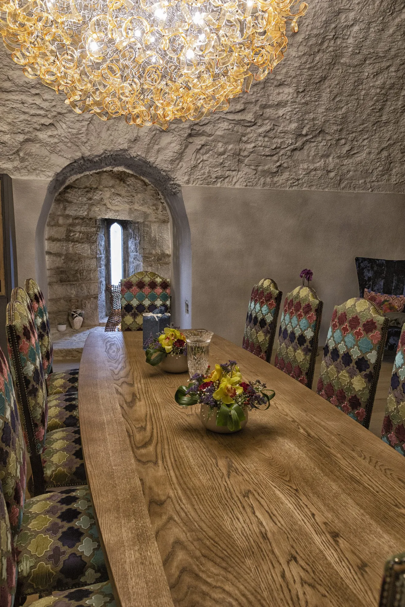 Long oak dining table set beneath the vaulted stone ceiling