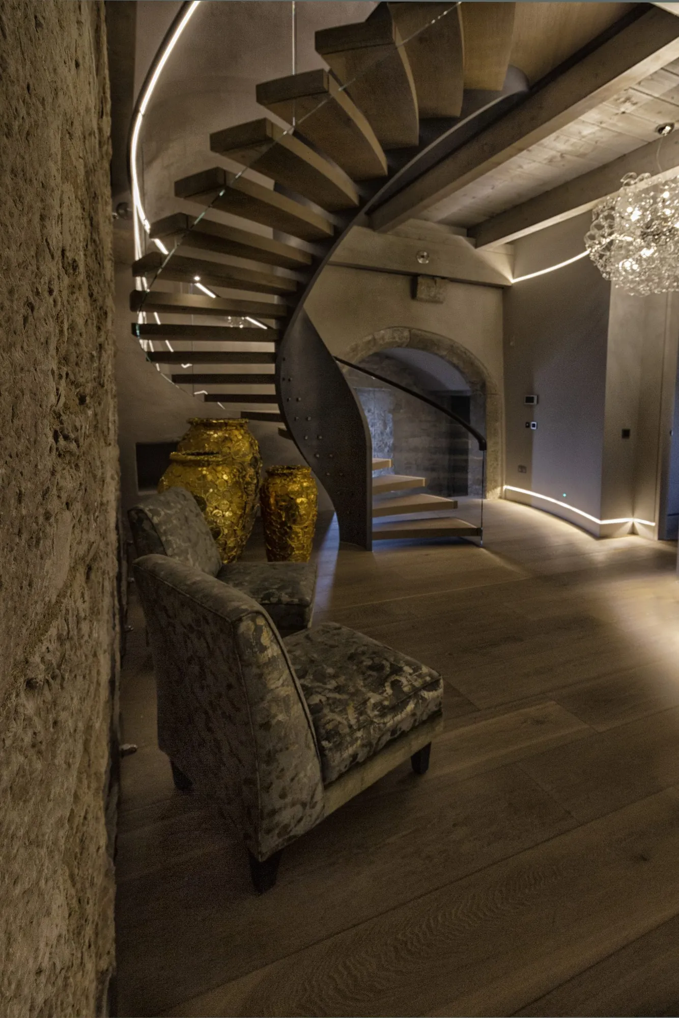 Curved staircase above a seating area within stone walls